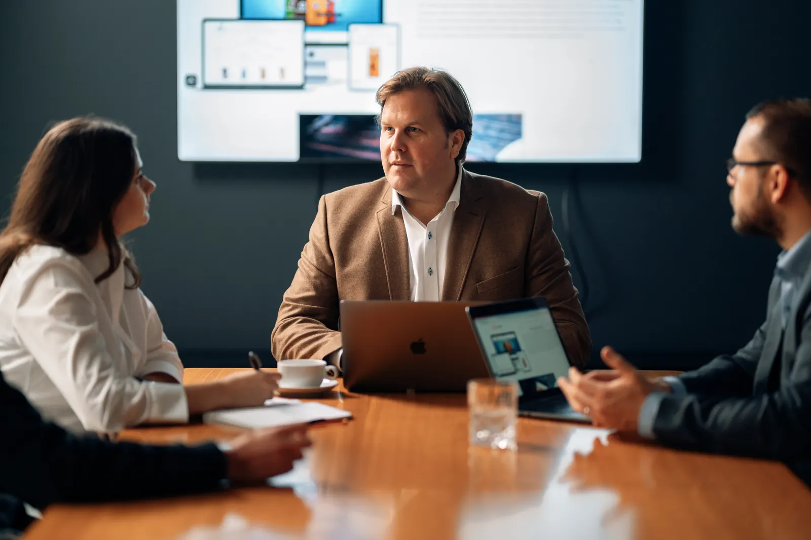 Holger Lentz im Projektgespräch mit dem Team, im Hintergrund Shop-Ansichten auf dem Bildschirm
